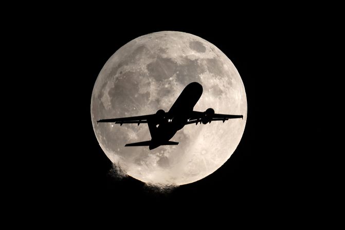 A plane flies below the full moon during the penumbral lunar eclipse in Shenyang, Liaoning Province, China.