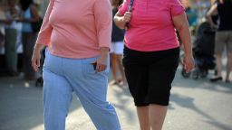 Two overweight women walk at the 61st Montgomery County Agricultural Fair on August 19, 2009 in Gaithersburg, Maryland. At USD 150 billion, the US medical system spends around twice as much treating preventable health conditions caused by obesity than it does on cancer, Health Secretary Kathleen Sebelius said. Two-thirds of US adults and one in five children are overweight or obese, putting them at greater risk of chronic illness like heart disease, cancer, stroke and diabetes, according to reports released recently at the  "Weight of the Nation" conference.   AFP PHOTO / Tim Sloan (Photo credit should read TIM SLOAN/AFP via Getty Images)