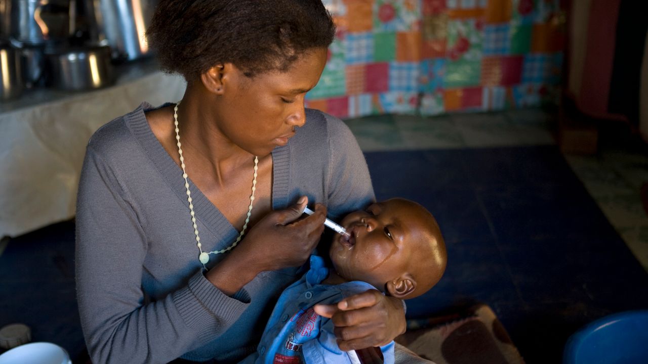 File photo. A mother in Lesotho gives her baby a dose of HIV medicines. 