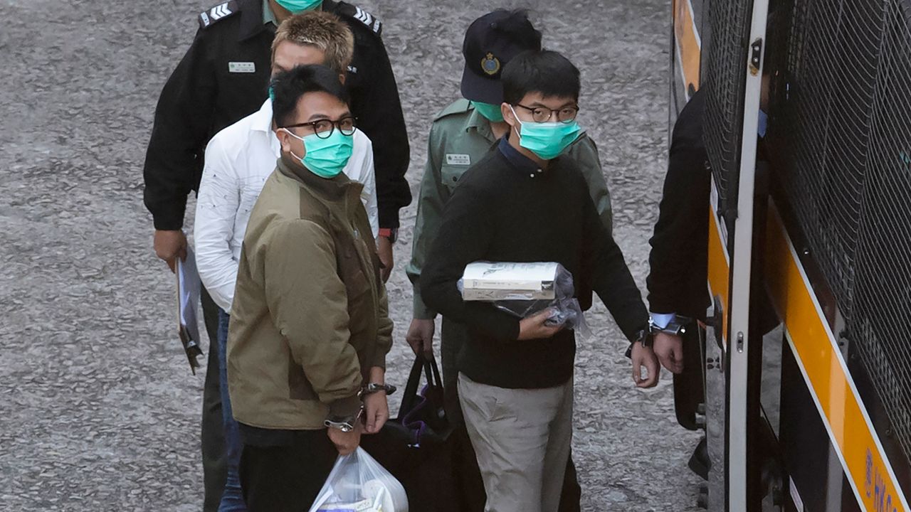 Hong Kong activists Joshua Wong, right, and Ivan Lam, left, are escorted by Correctional Services officers to get on a prison van before appearing in a court, in Hong Kong, Wednesday, December 2, 2020. 
