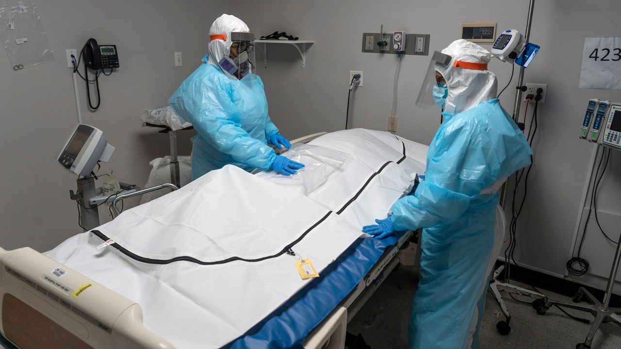 HOUSTON, TX - NOVEMBER 25: (EDITORIAL USE ONLY) (EDITORS NOTE: Image depicts death.) Medical staff members stand by a body bag that contains a deceased COVID-19 patient's body in the COVID-19 intensive care unit at the United Memorial Medical Center on November 25, 2020 in Houston, Texas. According to reports, Texas has reached over 1,210,000 cases, including over 21,300 deaths.  (Photo by Go Nakamura/Getty Images)