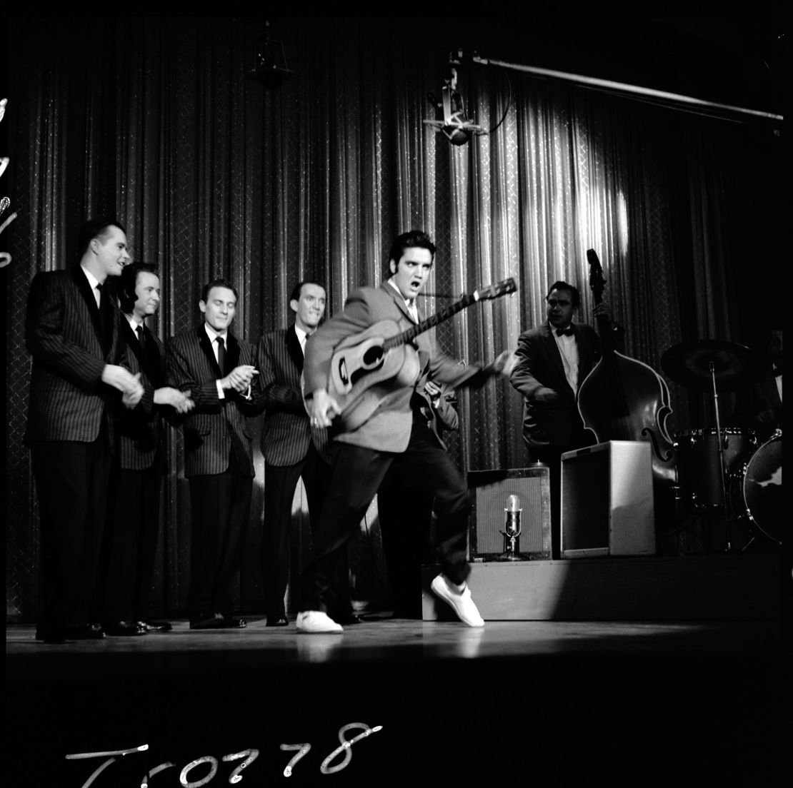 American singer and musician Elvis Presley swivels his hips as he performs with his band onstage during his second appearance on "The Ed Sullivan Show," on October 28, 1956. 