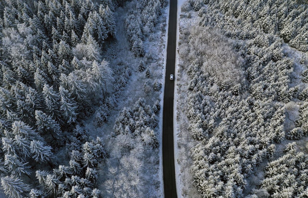 A car drives through a snow-covered forest in Ruderatshofen, Germany, on Thursday, December 3.