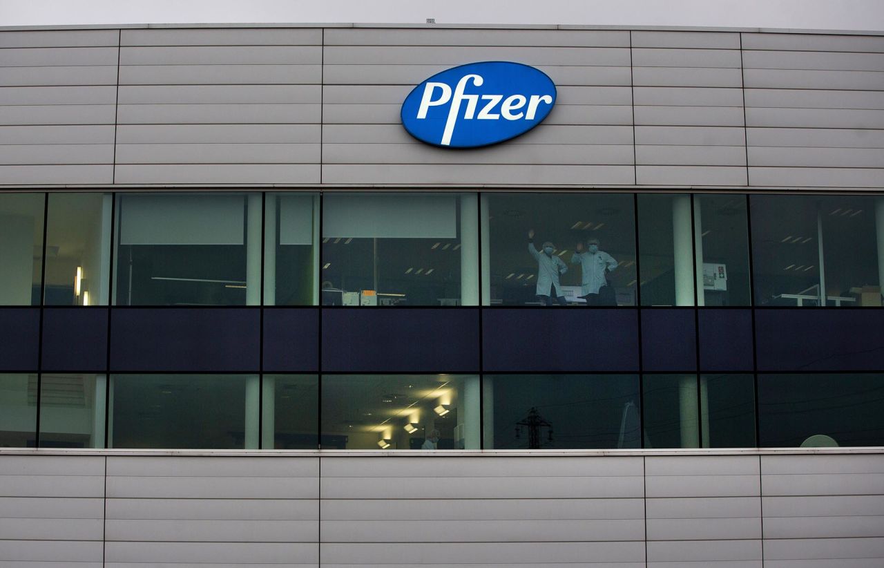 Two workers wave from inside a Pfizer manufacturing site in Puurs, Belgium, on Wednesday, December 2. Regulators in the United Kingdom <a href="https://www.cnn.com/2020/12/02/uk/pfizer-coronavirus-vaccine-uk-intl-hnk/index.html" target="_blank">have granted emergency authorization</a> for a Covid-19 vaccine made by Pfizer and its German partner BioNTech. The UK is the first Western nation to authorize a Covid-19 vaccine.