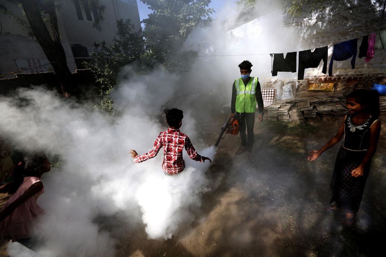 A boy plays in smoke as a municipal worker fumigates a residential area in Ahmedabad, India, on Thursday, December 3.