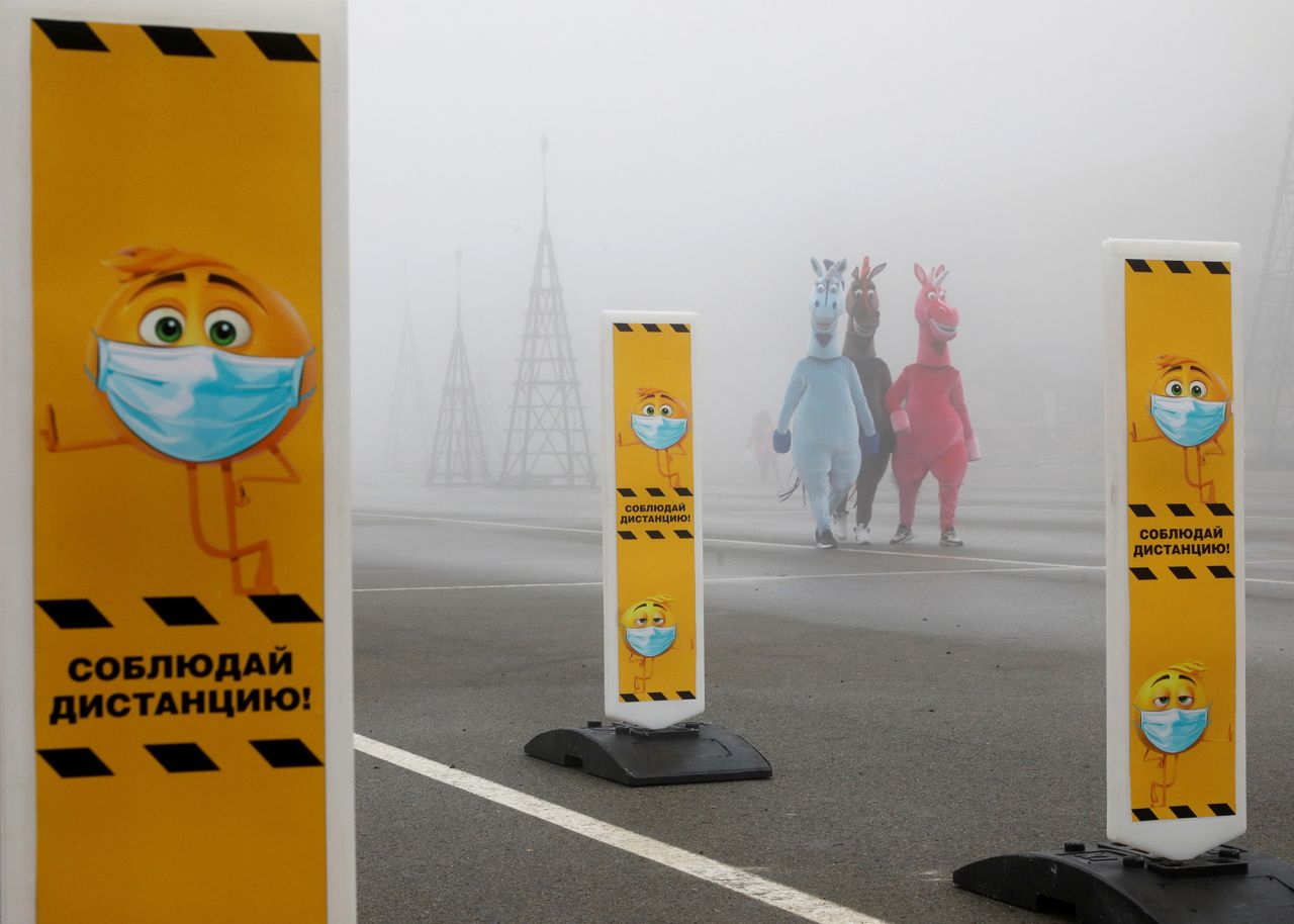People in costumes walk near signs encouraging social distancing in Stavropol, Russia, on Tuesday, December 1.