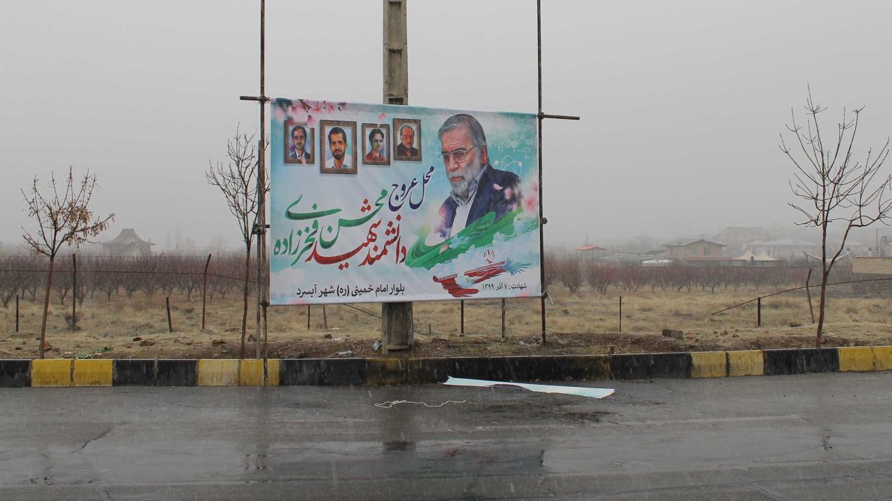 A poster of Mohsen Fakhrizadeh  stands above the spot where he was gunned down outside Tehran. 