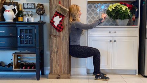 Fitness expert Dana Santas suggests getting in some core and leg-strengthening wall sits while you're checking your phone during this hectic time of year.