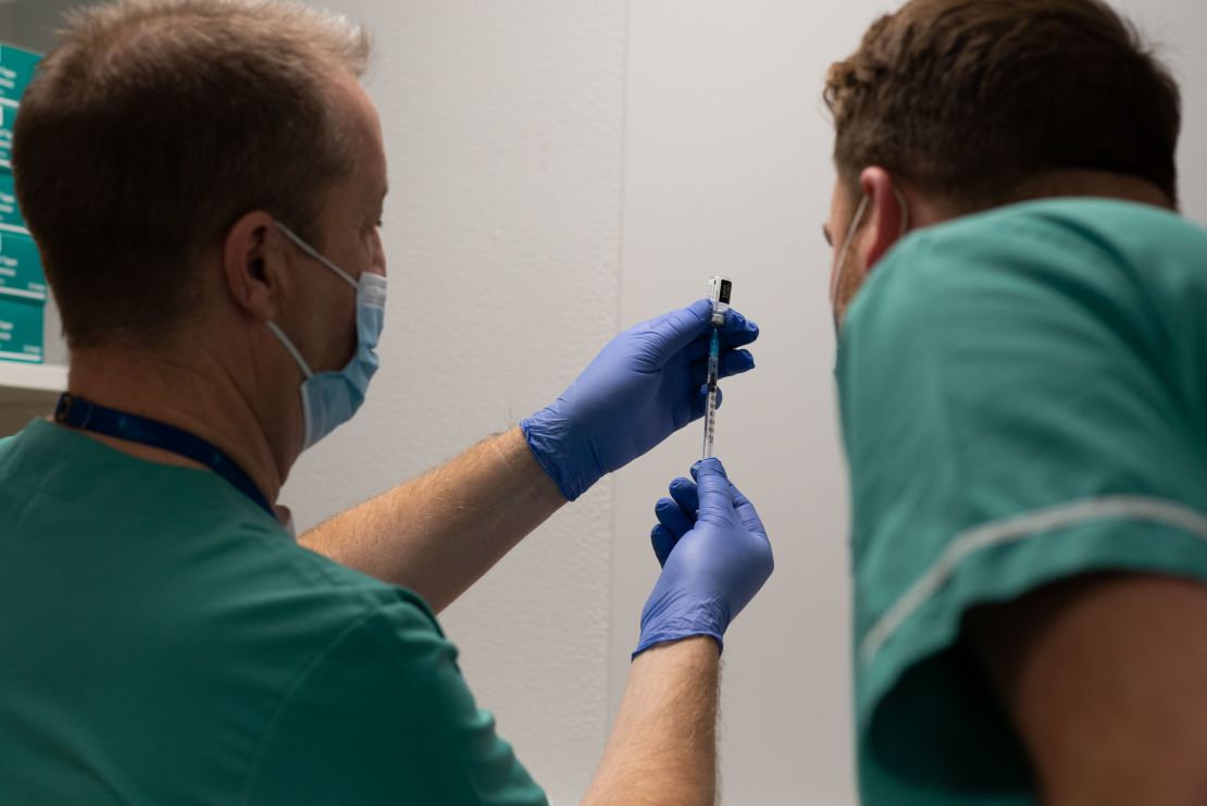 Darrell Baker (L), clinical director for pharmacy on Cardiff's health board, loads a syringe with the vaccine alongside senior pharmacy technician Rhys Oats.