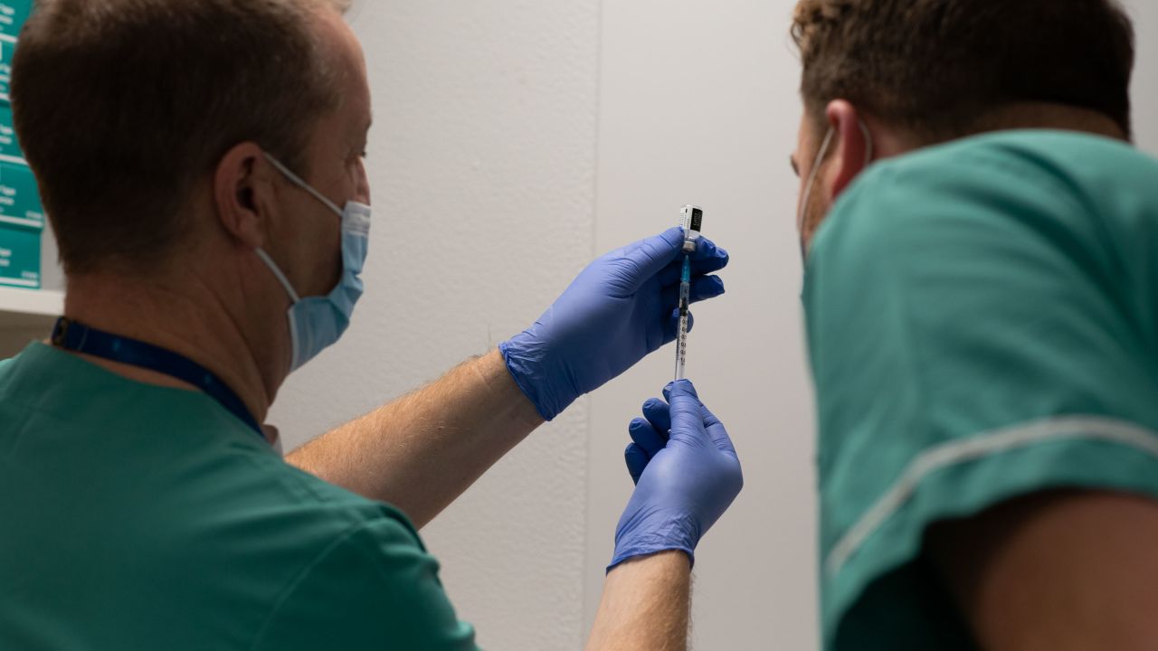 Darrell Baker (L), clinical director for pharmacy on Cardiff's health board, loads a syringe with the vaccine alongside senior pharmacy technician Rhys Oats.