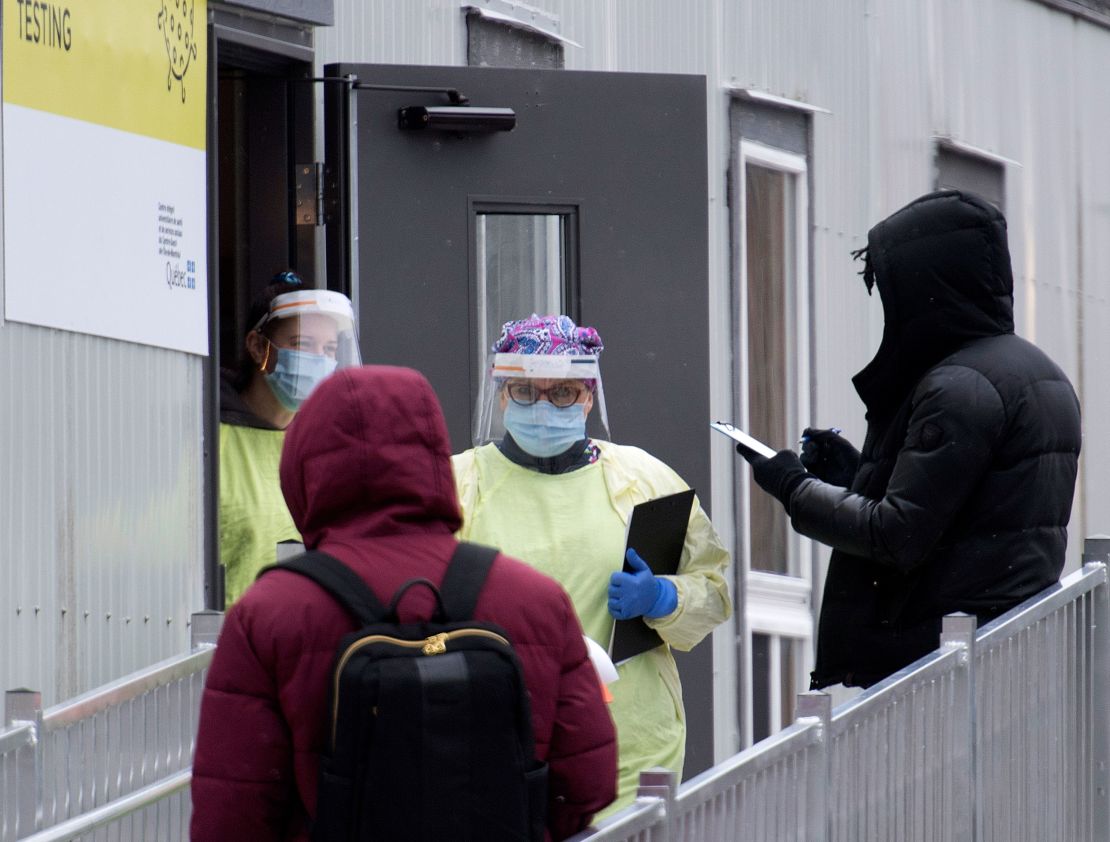 Health care workers talk to people waiting to tested for Covid-19 at a clinic in Montreal on Sunday, December 6.