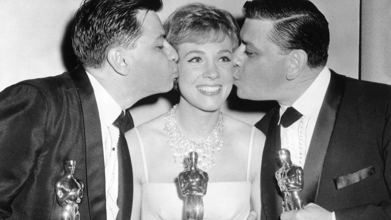 Richard Sherman (left) and Robert Sherman (right) with Julie Andrews (center) hold their Oscar statues in 1965 for their work on the film Mary Poppins.