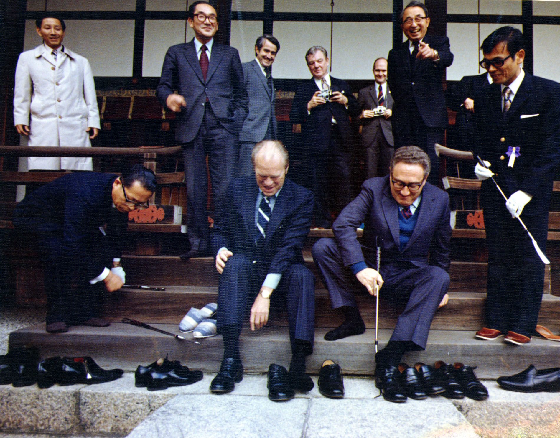 Kissinger and US President Gerald Ford remove their shoes during a visit to Japan in 1974.