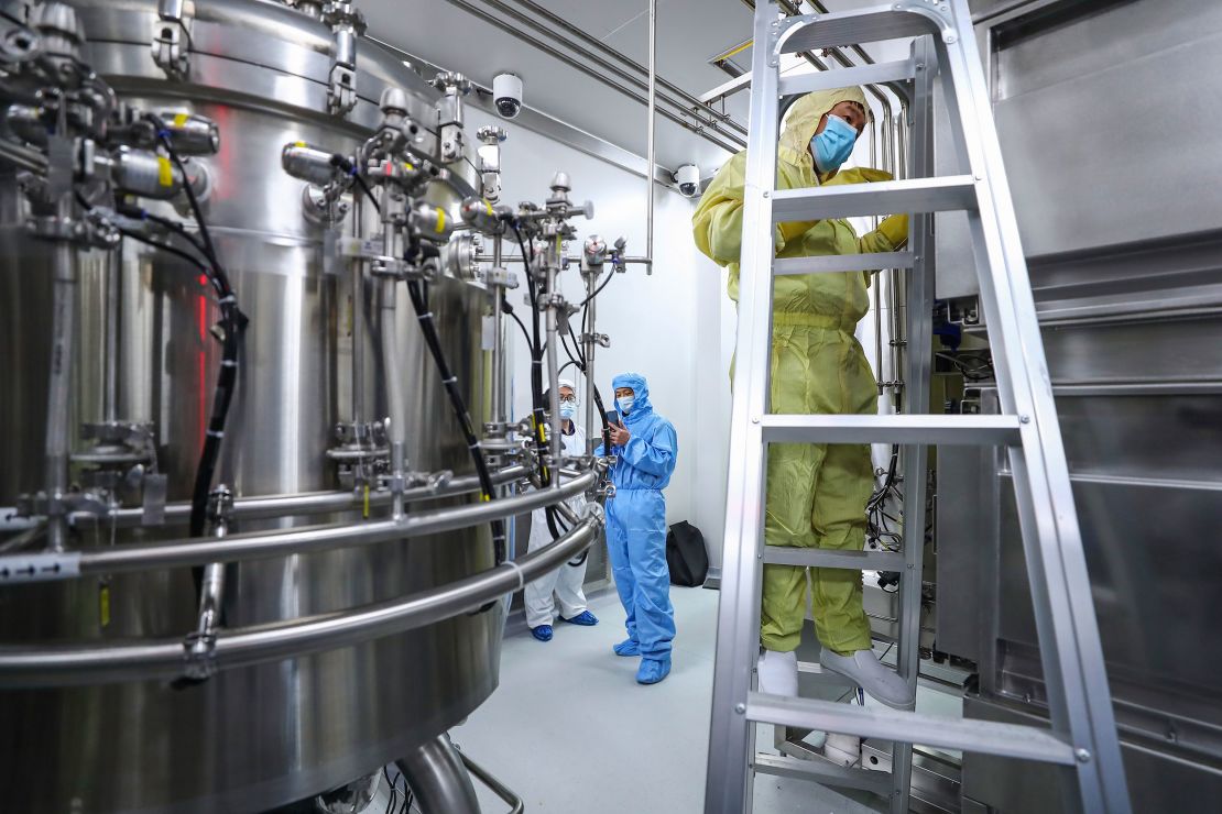 In this April 11, 2020, photo released by Xinhua News Agency, staff members check and clean equipments at a vaccine production plant of SinoPharm in Beijing.