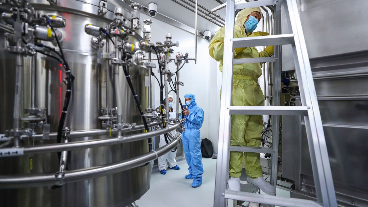 In this April 11, 2020, photo released by Xinhua News Agency, staff members check and clean equipments at a vaccine production plant of SinoPharm in Beijing.