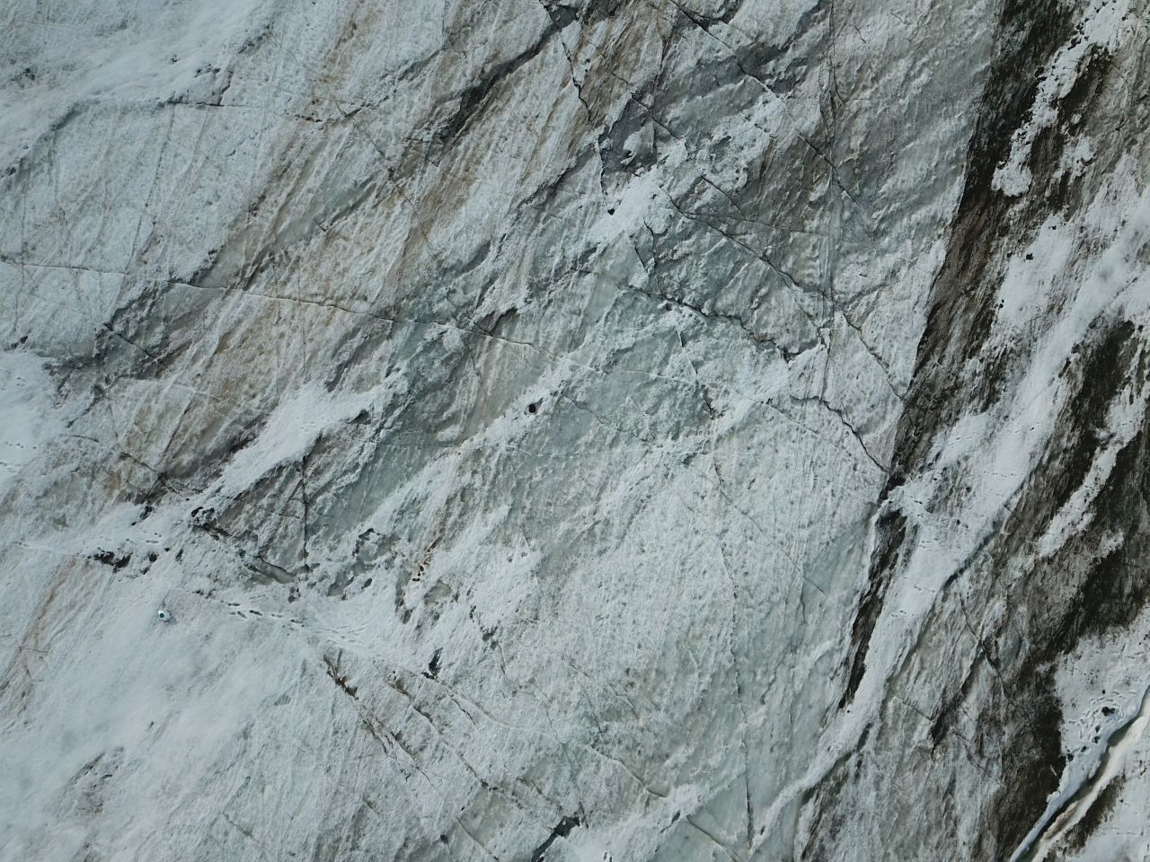 From above, Cook's image of Svalbard's Foxfonna Glacier shows the surface ravaged by crevasses, patches of rotten snow, bare ice and patches of dust and algae.