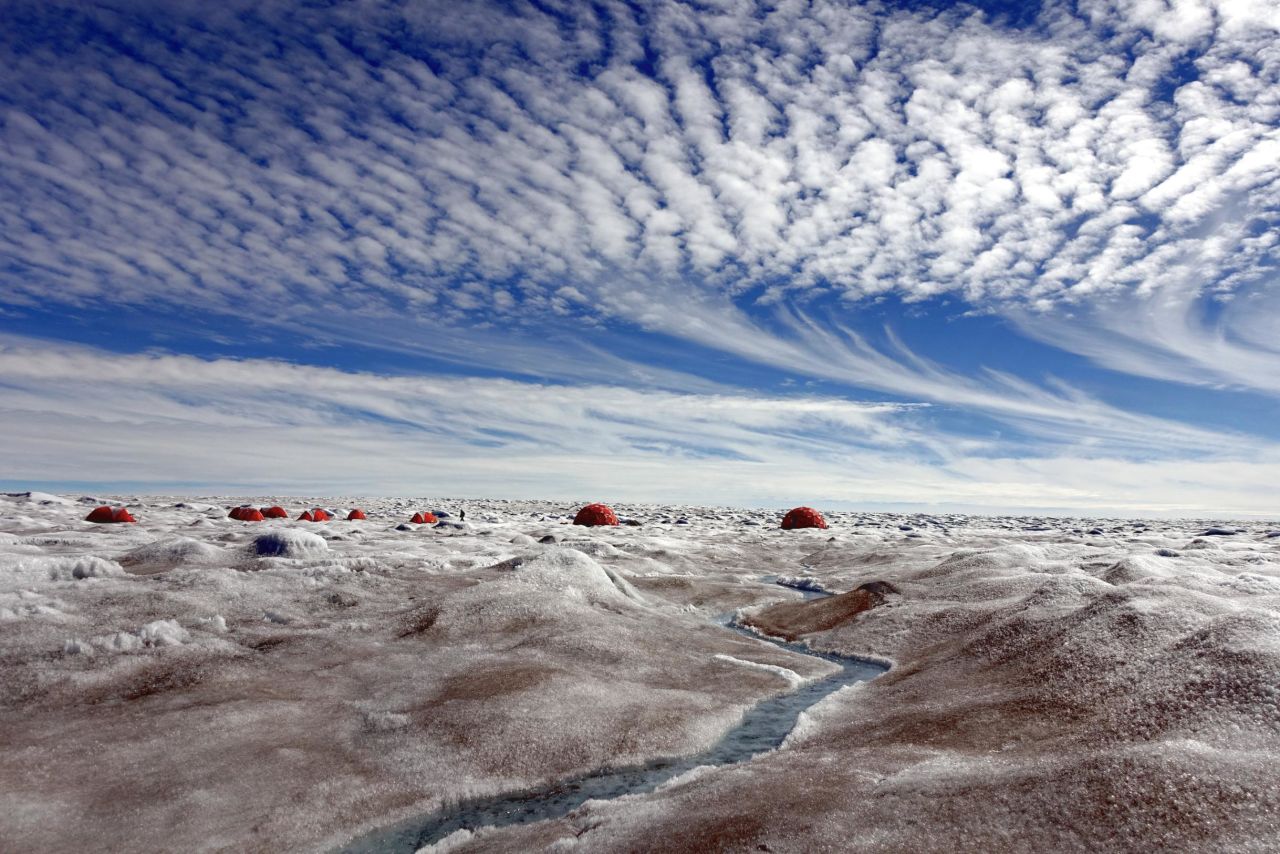 The surface of Greenland's ice sheet is darkened by a type of algae that speeds up the ice melt. The algae produces a pigment that acts like a "natural sunscreen" and gives protection from the Arctic sunlight. The pigment causes the ice underneath to melt. A group of scientists from the UK's National Environmental Research Council project "Black and Bloom" set up camp on the ice sheet in 2016 to study the impact of these microbes on the ice.