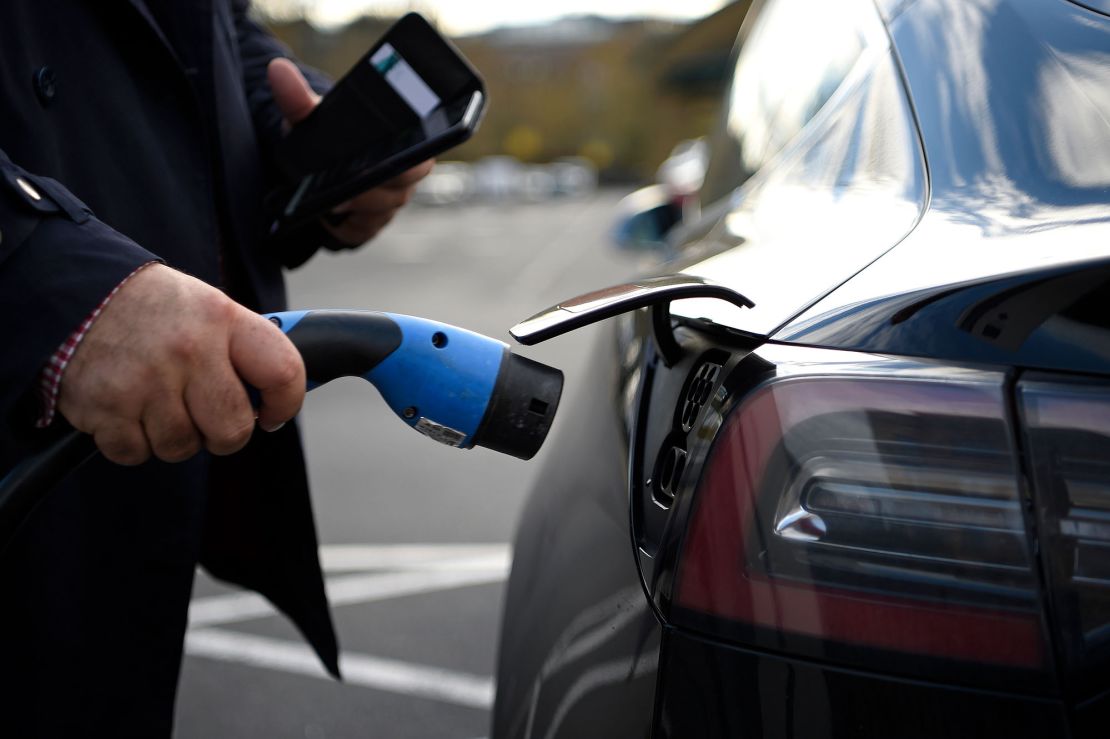A customer prepares to charge a Tesla electric car at a supermarket in north London.