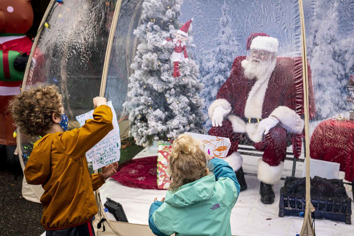 Mateo and Neah Johnson show Santa their letters while visiting him at a socially distanced snow globe in Seattle on Sunday, December 6.