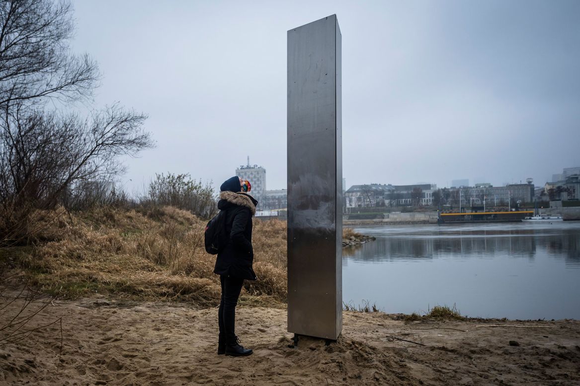 A woman looks at a metal monolith that popped up on a riverbank in Warsaw, Poland, on Thursday, December 10. <a href="https://www.cnn.com/videos/style/2020/12/09/mysterious-monoliths-spotted-across-the-world-lon-orig-na.cnn" target="_blank">Similar monoliths have popped up</a> in Romania, the United Kingdom and the United States.