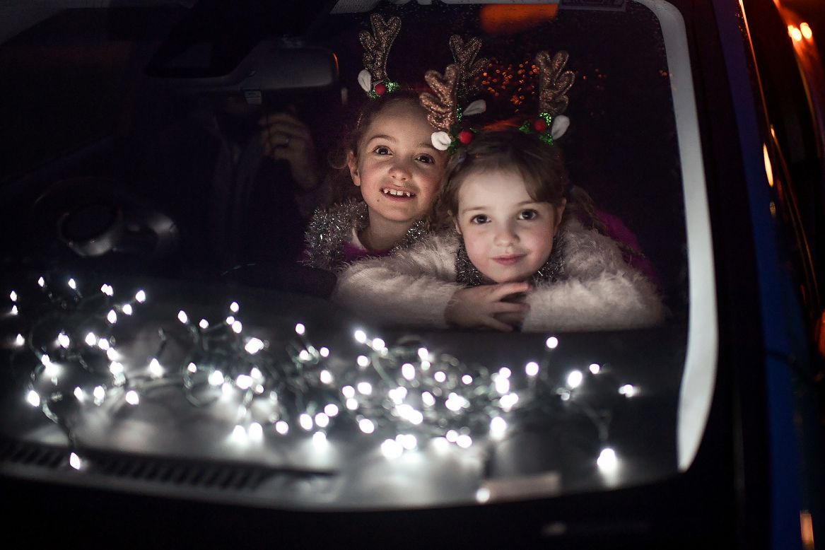 Two girls look out of a car window as they attend a drive-in movie at a school in Perth, Scotland, on Thursday, December 10.