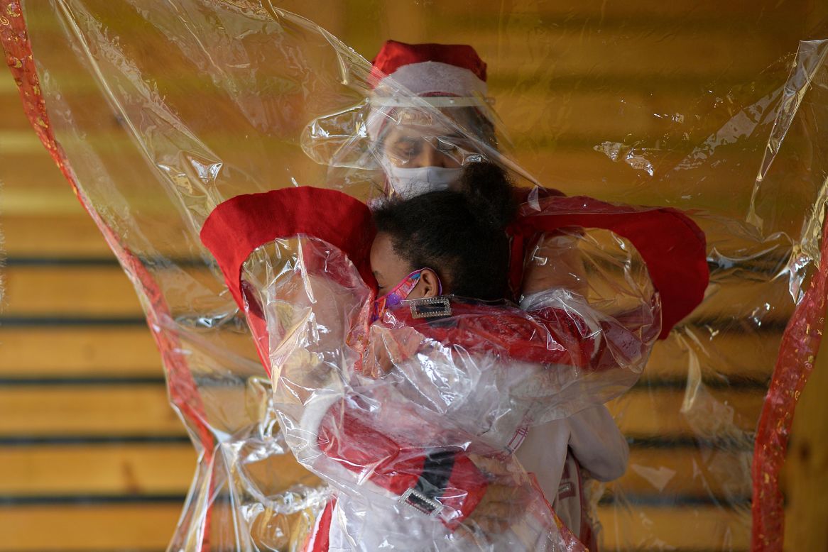 Fatima Sanson, dressed up as Mrs. Claus, embraces a child through plastic in Belo Horizonte, Brazil, on Monday, December 7. Every Christmas season, Sanson delivers hugs and gifts to needy children.