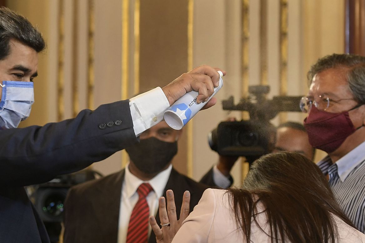 Venezuelan President Nicolas Maduro playfully sprays disinfectant on a journalist as he leaves a news conference in Caracas on Tuesday, December 8.