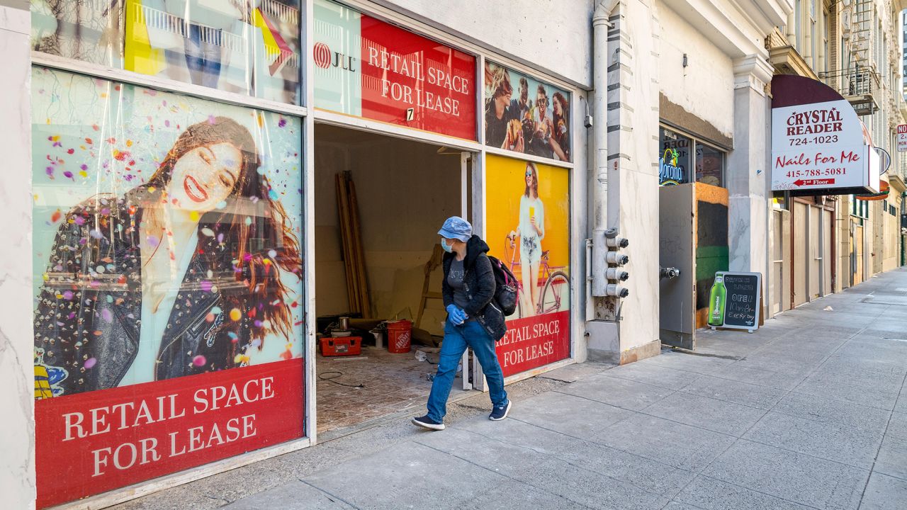 A person wearing a protective mask walks past a store for lease in San Francisco, California, U.S., on Tuesday, Dec. 8, 2020. 