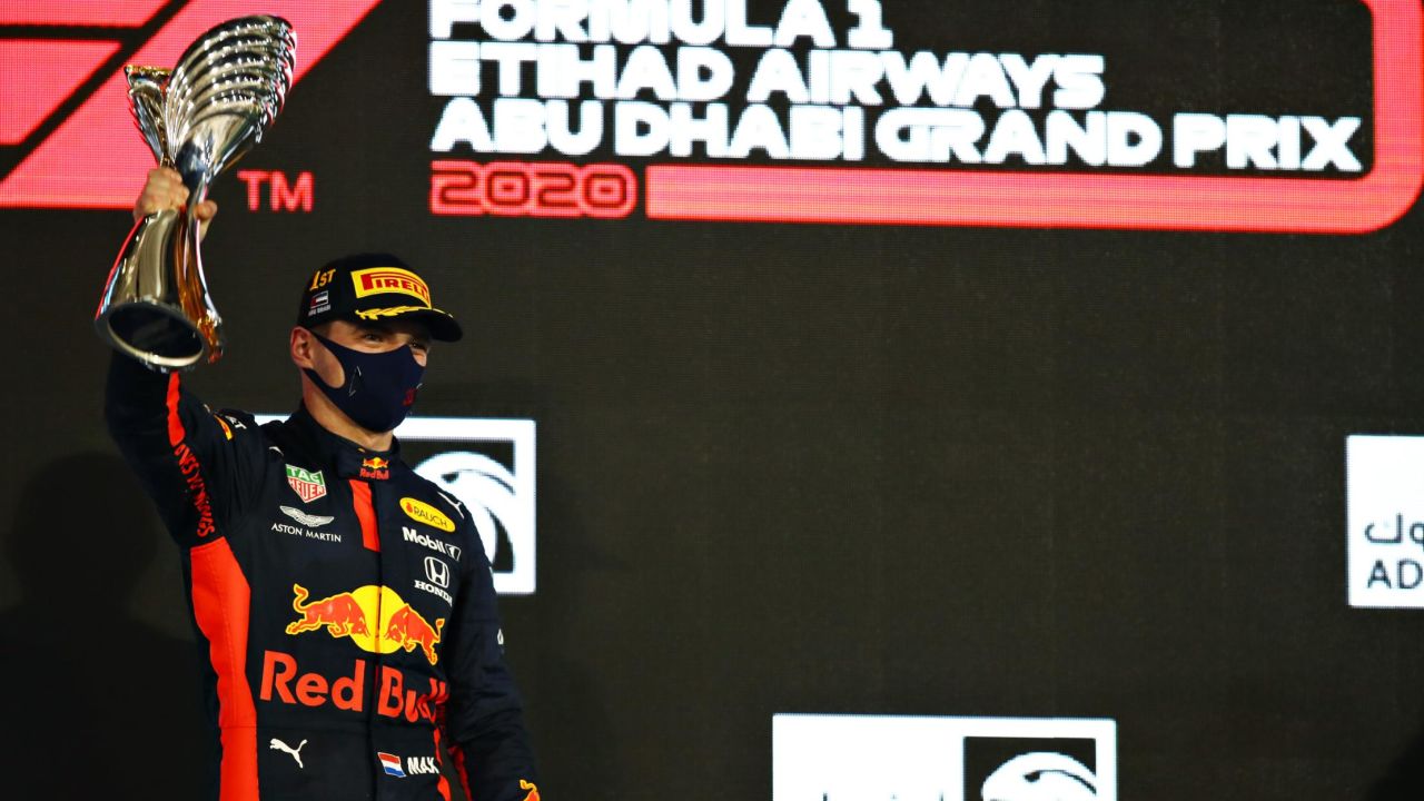 Verstappen stands on the podium with his trophy.