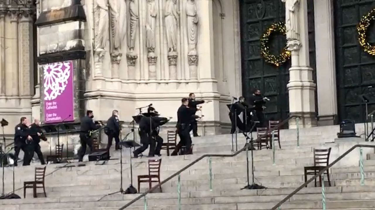 New York police officers move in on the scene of a shooting at the Cathedral Church of St. John the Divine, Sunday, Dec. 13, 2020, in New York. A man was shot by police after shots rang out at the end of a Christmas choral concert on the steps of the Manhattan cathedral Sunday afternoon. It's unclear if the gunman was killed or if any others were injured. The shooting happened just before 4 p.m. at the church which is the mother church of the Episcopal Diocese of New York and seat of its bishop. (AP Photo/Ted Shaffrey)