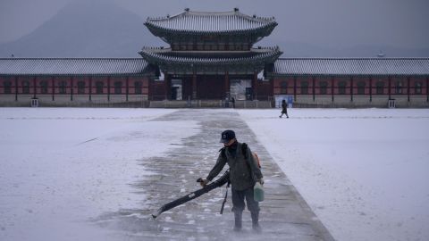 A worker uses a blower to clear snow from a courtyard at Gyeongbokgung palace in central Seoul on December 13, 2020.
