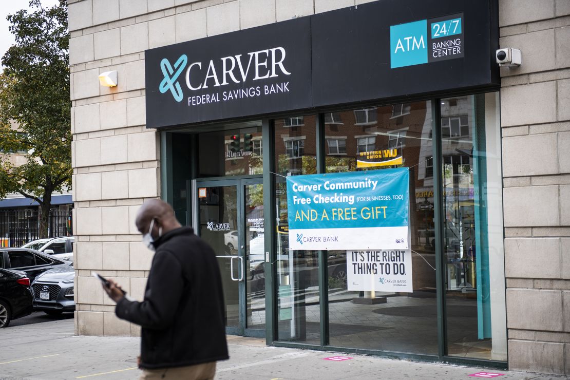 A pedestrian wearing a protective mask walks past a Carver Federal Savings Bank branch in the Harlem neighborhood of New York City on Tuesday, Oct. 27, 2020.