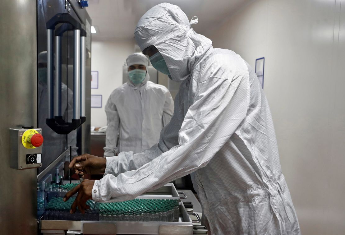 An employee removes vials of AstraZeneca's Covishield vaccine from a visual inspection machine inside a lab at Serum Institute of India, Pune, India.