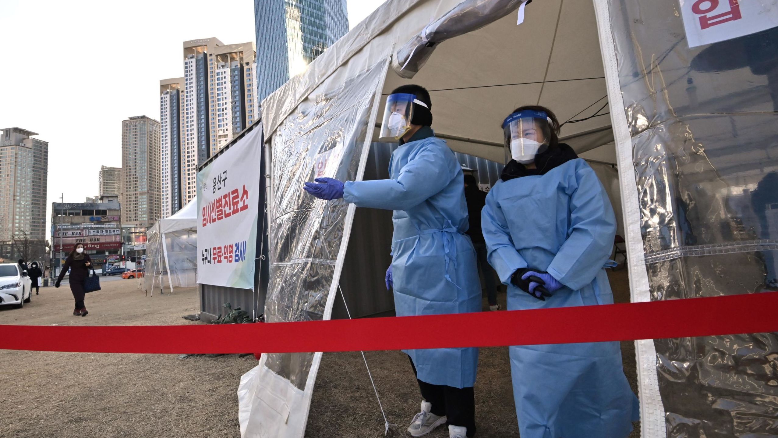 Health officials wearing protective gear guide visitors for the Covid-19 coronavirus test at a temporary testing station outside a railway station in Seoul on December 16, 2020.