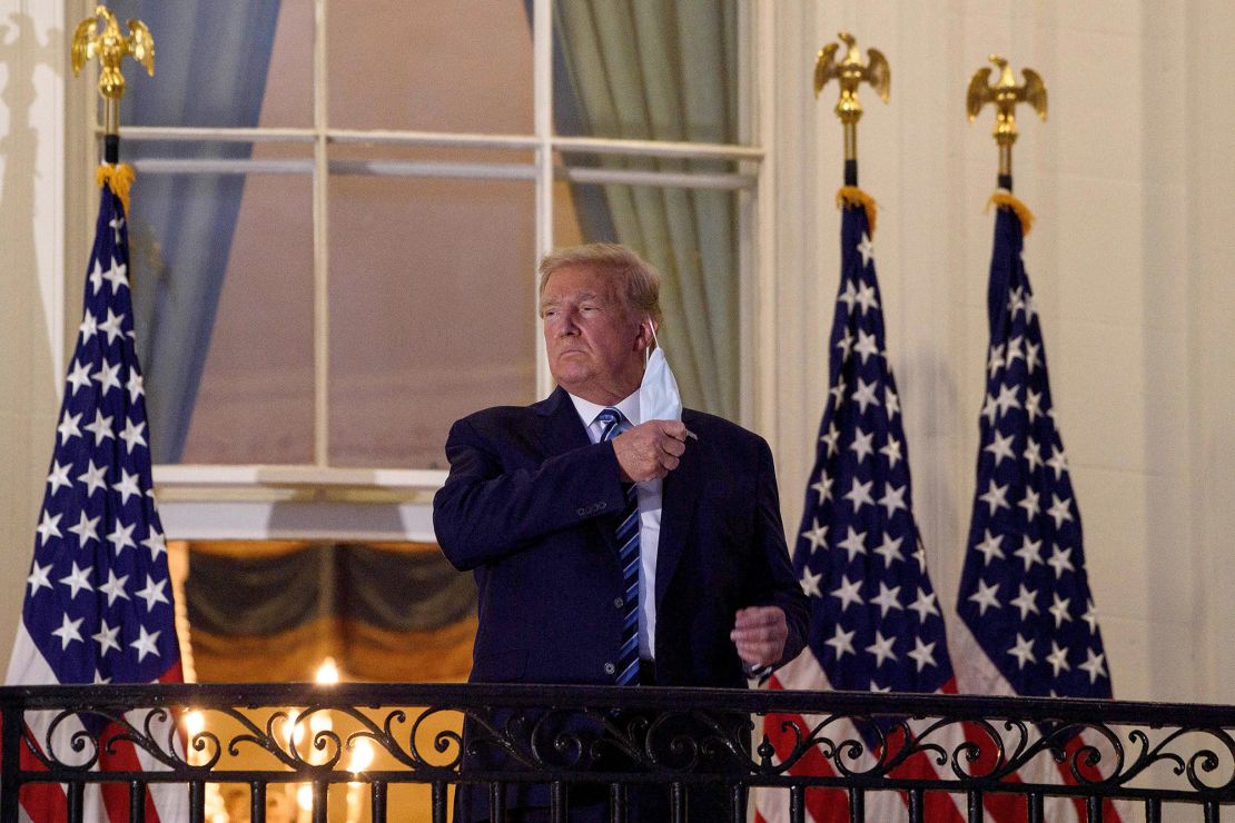 US President Donald Trump takes off his facemask as he arrives at the White House upon his return from Walter Reed Medical Center, where he underwent treatment for Covid-19.