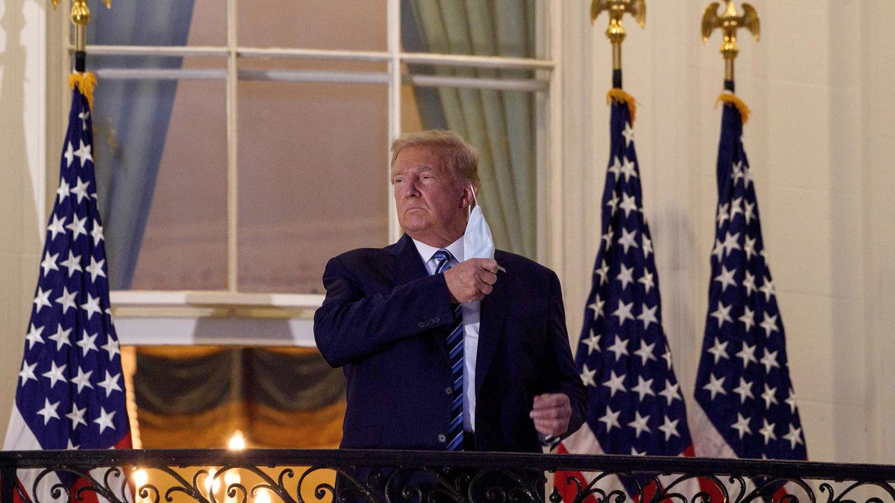 US President Donald Trump takes off his facemask as he arrives at the White House upon his return from Walter Reed Medical Center, where he underwent treatment for Covid-19.