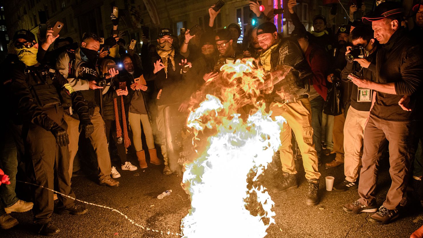 A protester adds fuel to a 'Black Lives Matter' flag on fire on December 12, 2020 in Washington, DC.