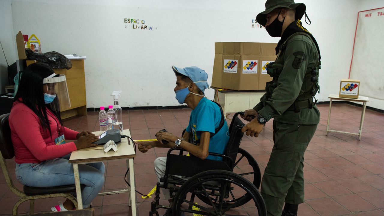 A soldier helps a man on a wheelchair as he votes at a polling station in a school in Caracas, on December 6.