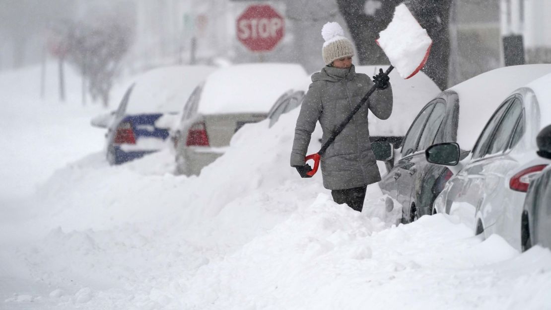 A woman tosses a shovel full of snow while digging out her car on Dec. 17, 2020, in Manchester, New Hampshire.