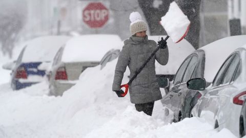 A woman tosses a shovel full of snow while digging out her car on Dec. 17, 2020, in Manchester, New Hampshire.