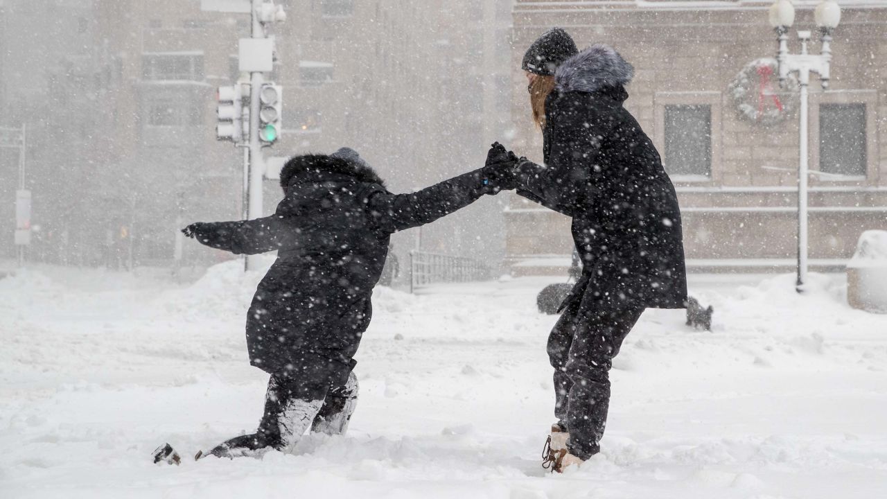 A woman helps her friend stand up after slipping on the sidewalk Thursday in Boston.