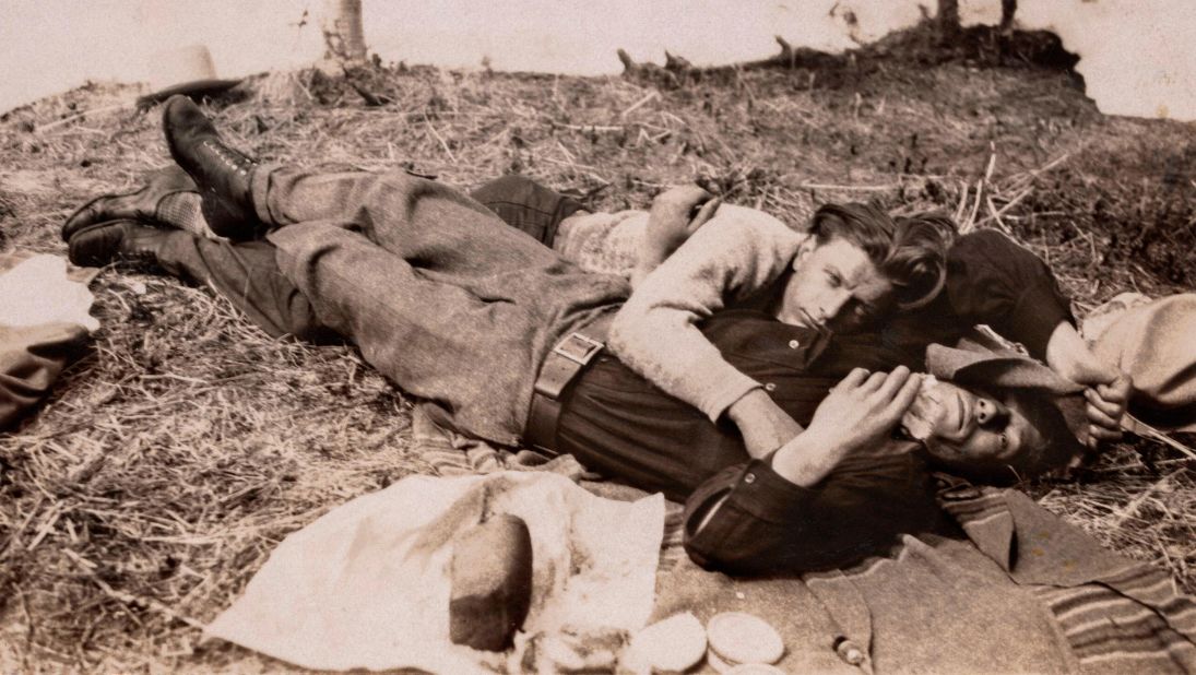 An undated photo shows two men lying out on the grass. 