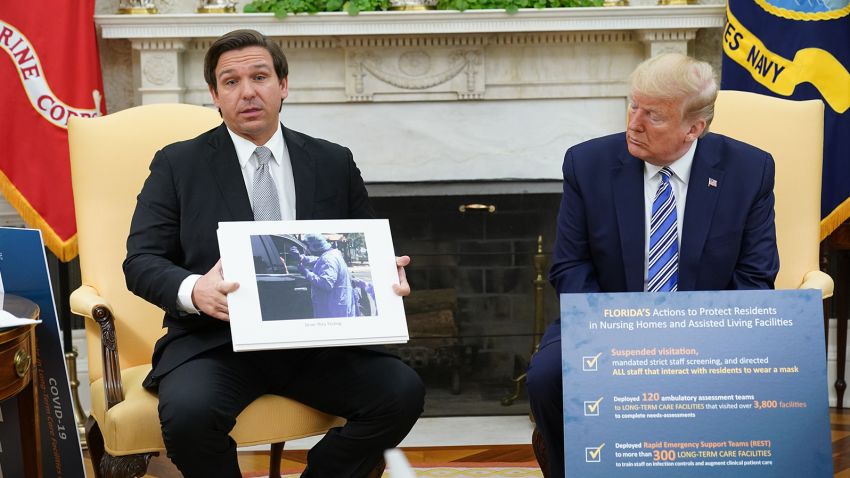US President Donald Trump listens as Florida Governor Ron DeSantis holds up a photo during a meeting in the Oval Office of the White House in Washington, DC on April 28, 2020. (Photo by MANDEL NGAN / AFP) (Photo by MANDEL NGAN/AFP via Getty Images)