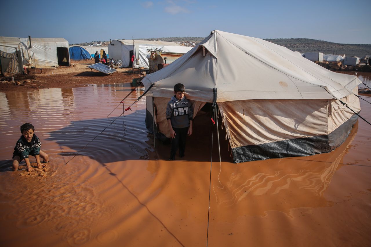 Two boys stand outside their tent on Thursday, December 17, after heavy rain flooded a refugee camp in Kafr Aruq, Syria.