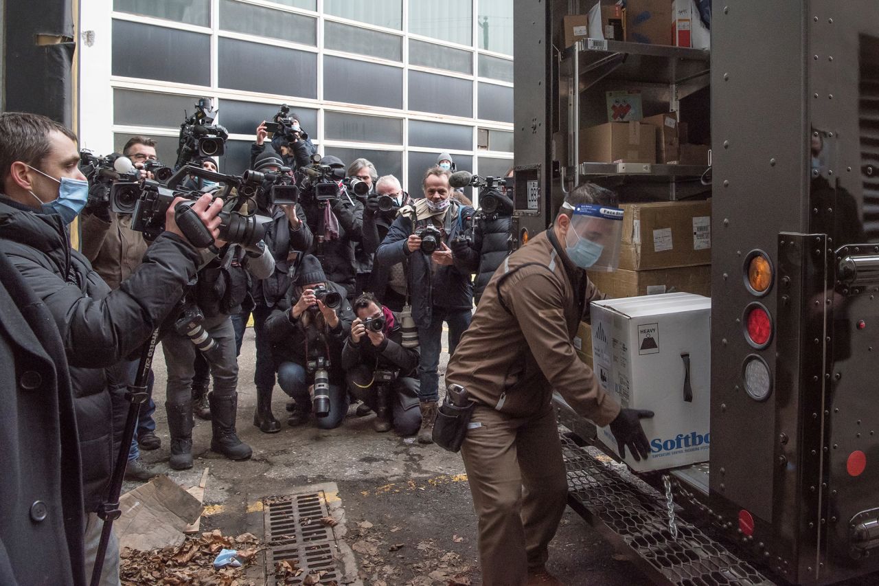 News photographers watch a man unload Covid-19 vaccines from a truck in Montreal on Monday, December 14.
