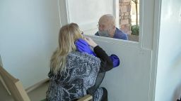 A nursing home resident holding a loved one using the hugging booth.