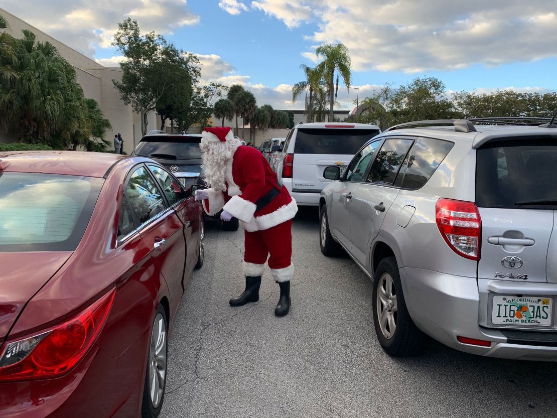 Santa spreads cheer to people waiting in line for food. Cadillacs and other expensive cars were in the line.