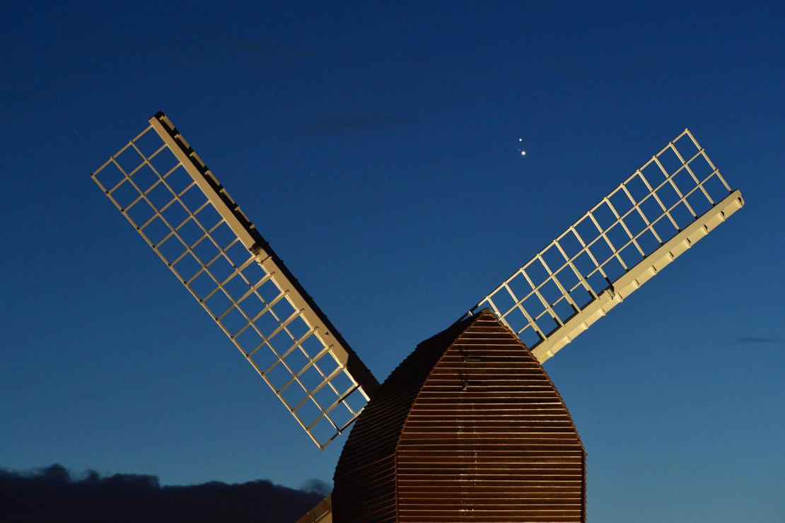 Jupiter and Saturn are seen coming together in the sky over the sails of Brill Windmill in Brill, England. 