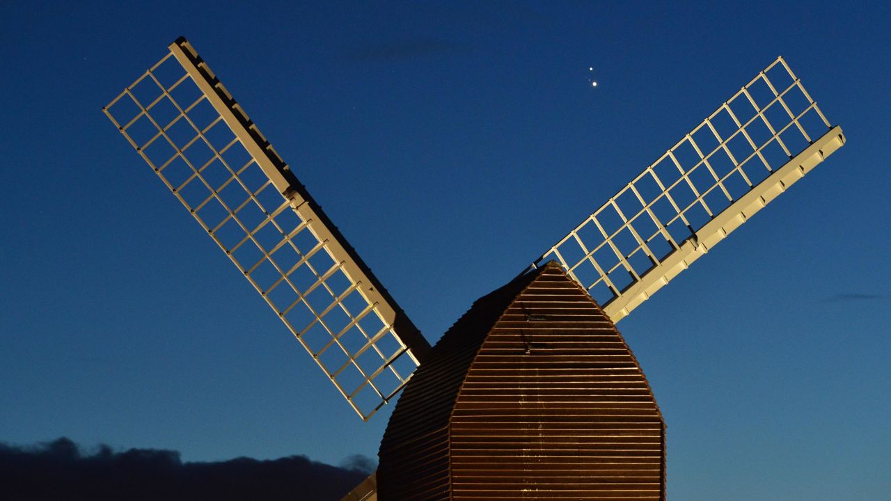 Jupiter and Saturn are seen coming together in the sky over the sails of Brill Windmill in Brill, England. 