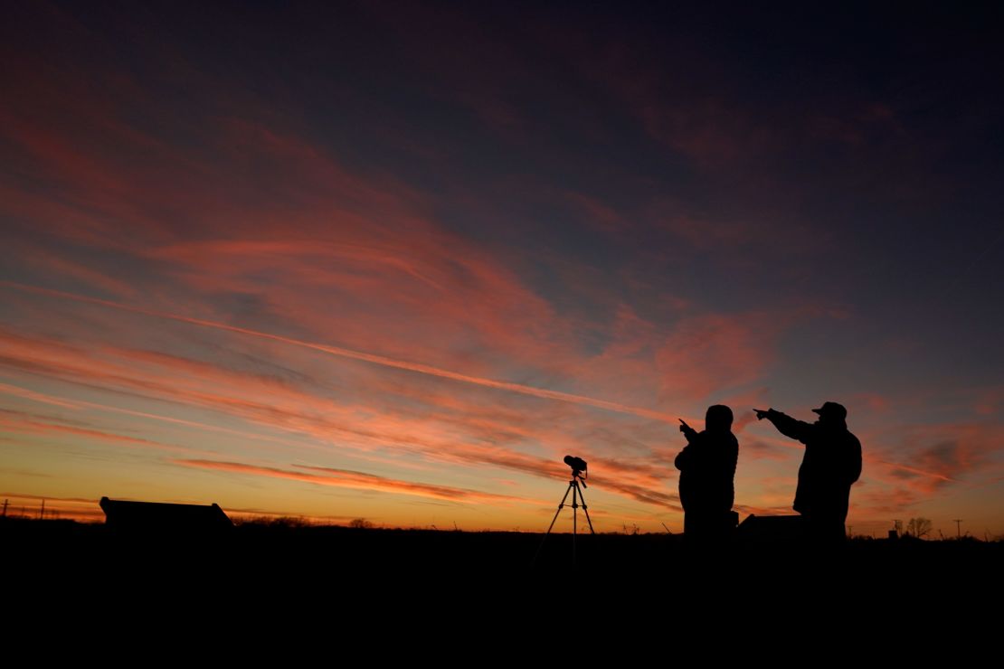People are silhouetted against the sky at dusk as they watch the alignment Monday in Edgerton, Kansas. 